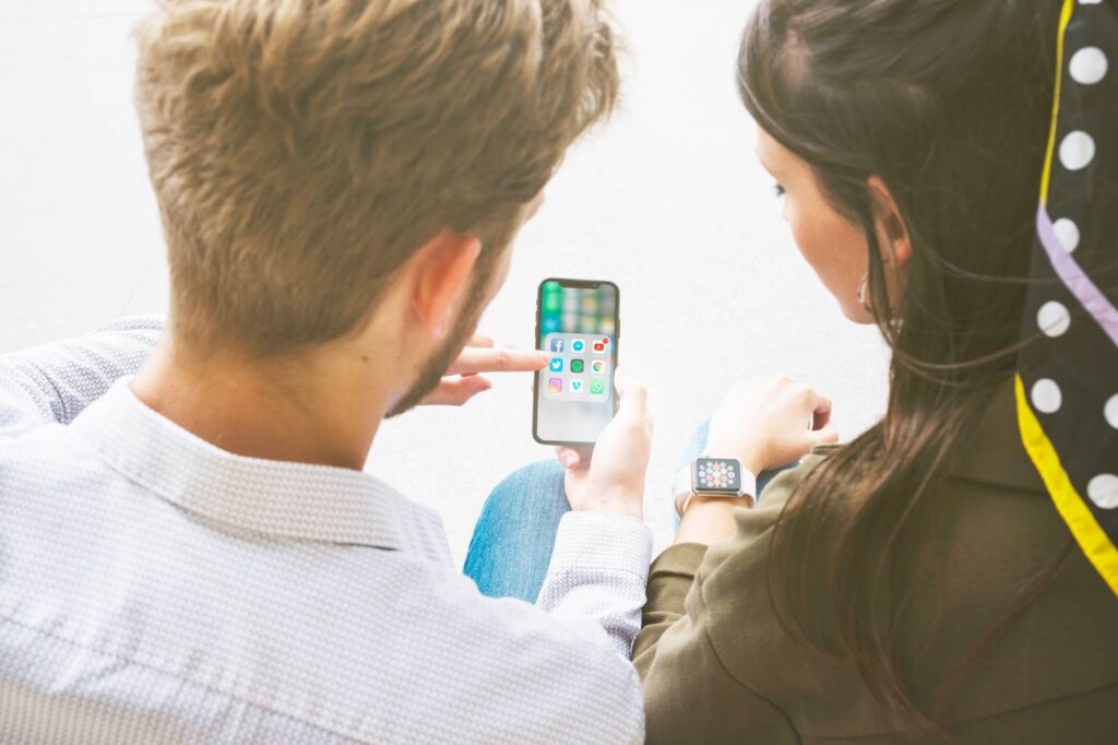 Two people looking at a smartphone together, reviewing mobile apps during an app installation decision