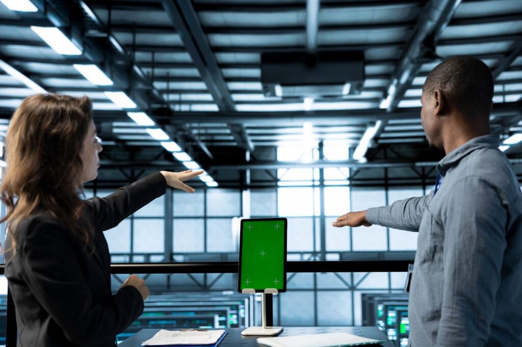 wo professionals gesturing toward a digital screen in a modern workspace, representing collaborative decision-making in a fast-moving digital environment