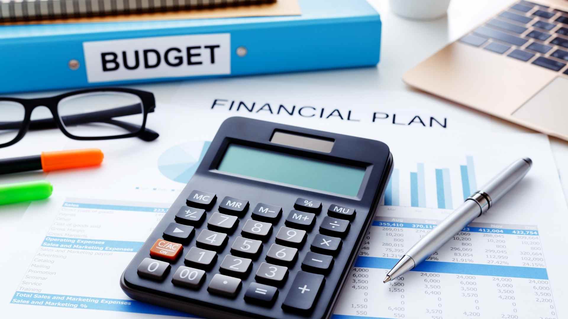 Calculator on financial planning documents with budget reports, charts, and business finance data for wealth management and budgeting