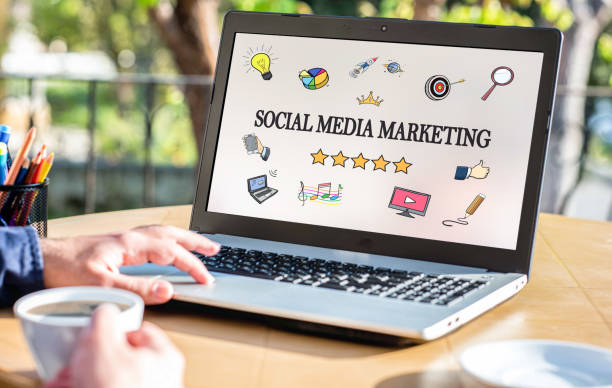 Laptop displaying a social media marketing graphic with icons, stars, and a person working at a desk.