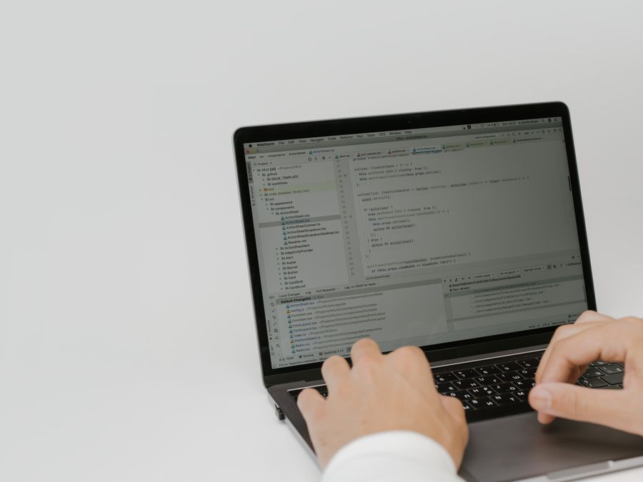 Hands typing code on a laptop in a workspace. Indoor setting focused on software development.
