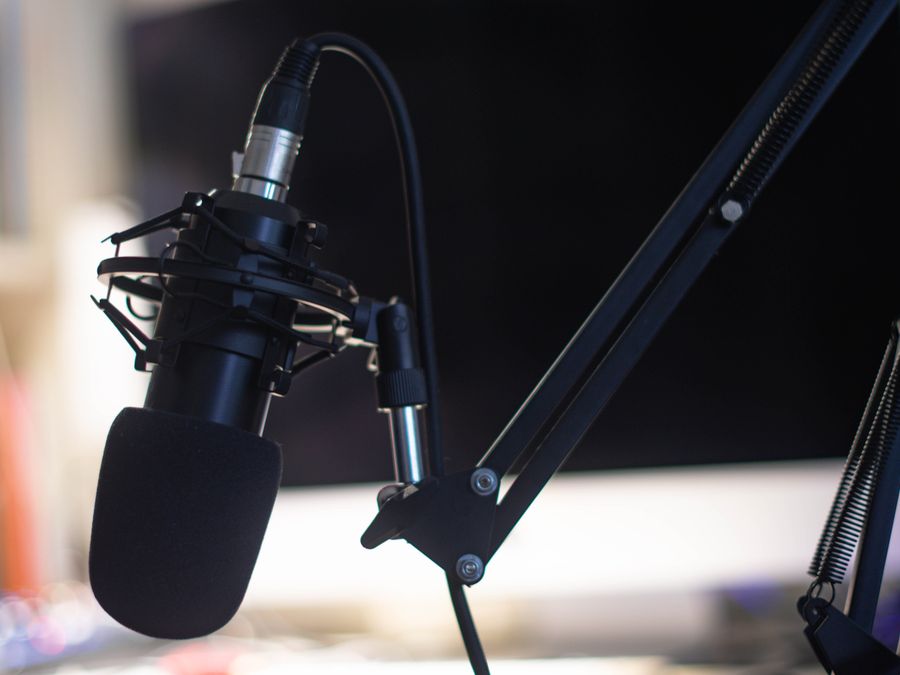 Close-up of a condenser microphone in a studio setting, ideal for podcasts and audio recording.