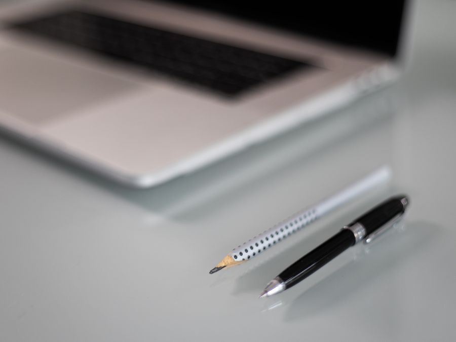 A close-up of a laptop on a desk with a pencil and pen, representing a modern workspace.