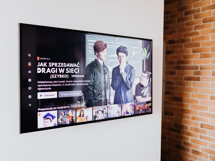 Smart TV displaying streaming content in modern living room setting with exposed brick wall.