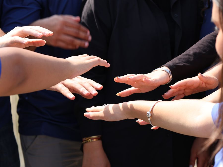 A diverse group of people placing hands together symbolizing teamwork and unity.