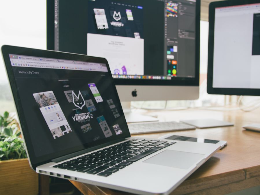 A stylish workspace featuring a laptop and monitors displaying design software.
