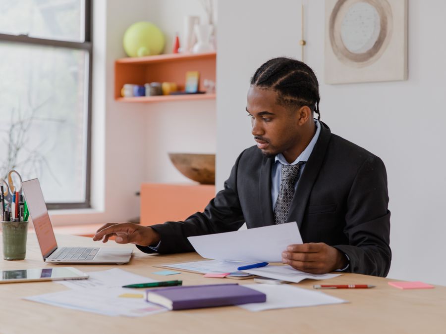 Focused businessman working with laptop and documents in a modern office setting.