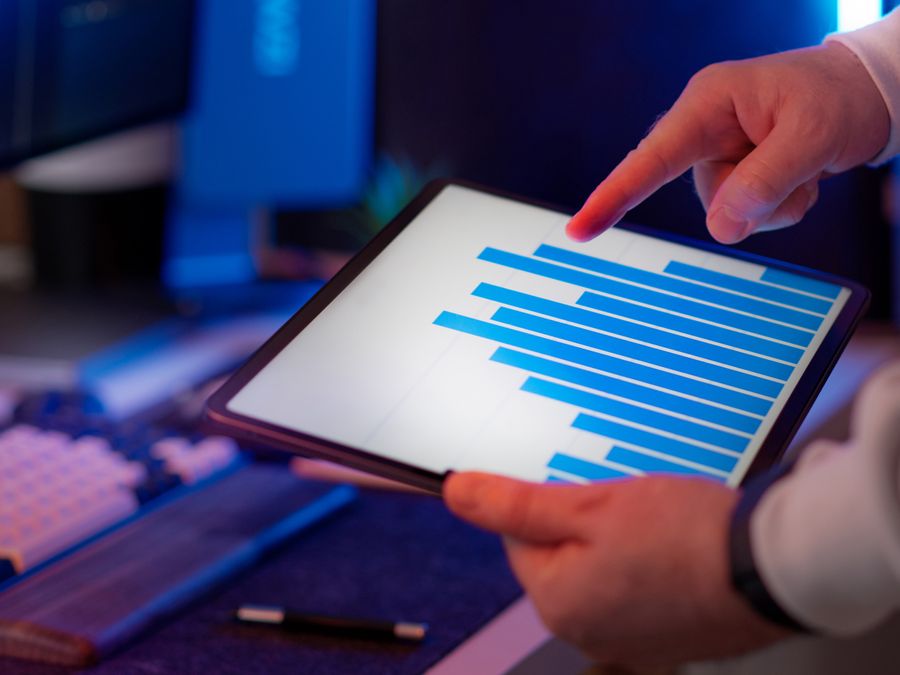 Business professional analyzing bar chart on tablet in office setting, highlighting data insights.