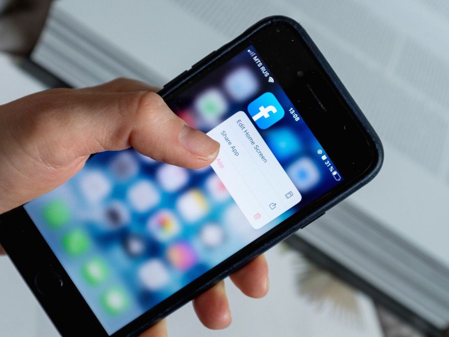 From above of crop anonymous person touching blurred cellphone screen while opening app and choosing option from pop up window