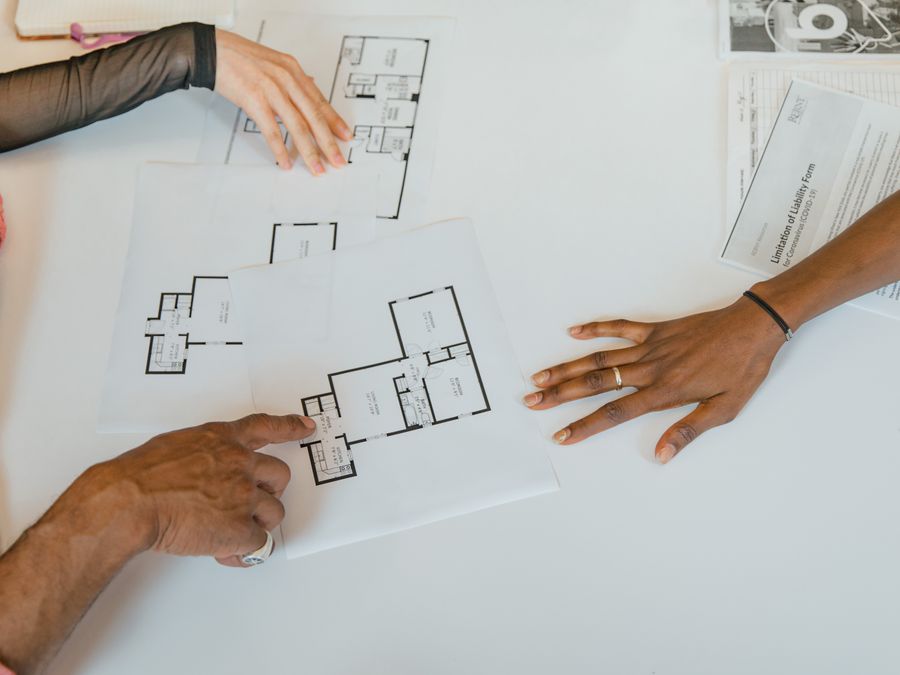 Overhead view of diverse team planning business strategy with floor plans.