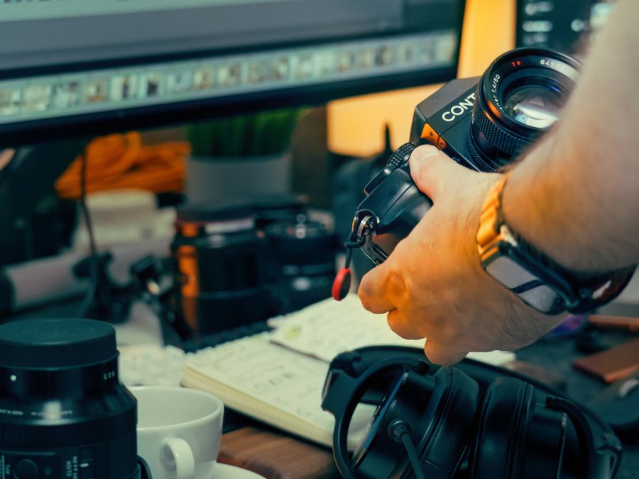 An artistic desk setup featuring vintage camera gear, monitors, and headphones, perfect for a creative photography workflow.