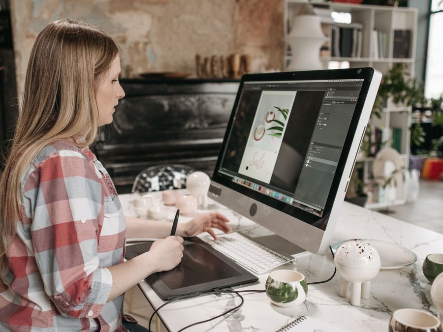Woman using a digital drawing tablet in a stylish office workspace, focused on graphic design.
