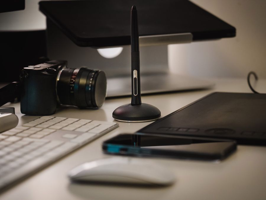 A sleek office desk featuring tech gadgets including a camera and digital drawing tablet.