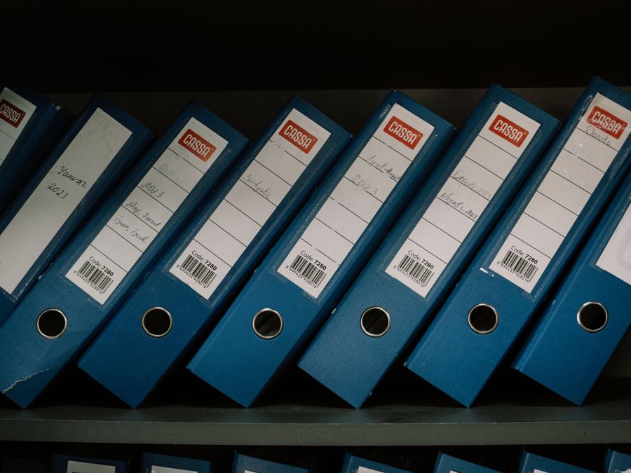 Neatly arranged blue office binders labeled with dates and names for organized storage.
