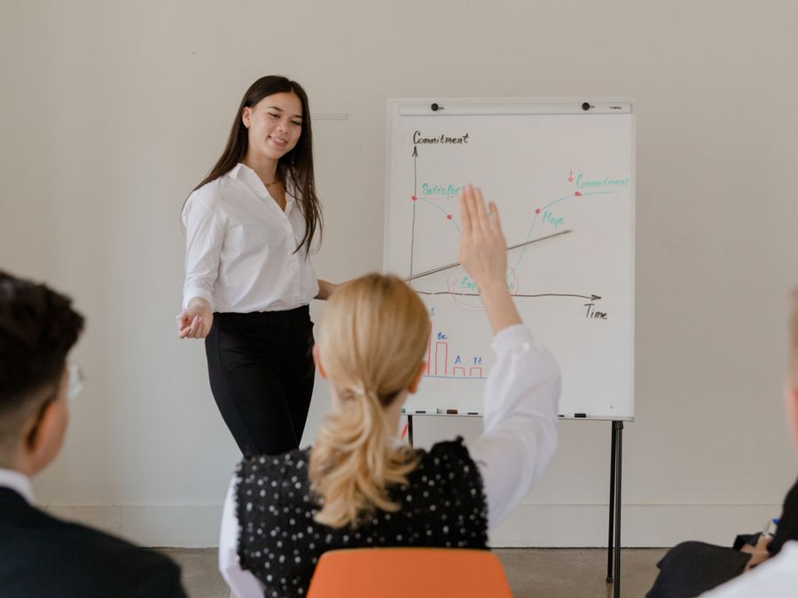 A businesswoman leads a meeting with a graph presentation, engaging her audience. Professional setting.