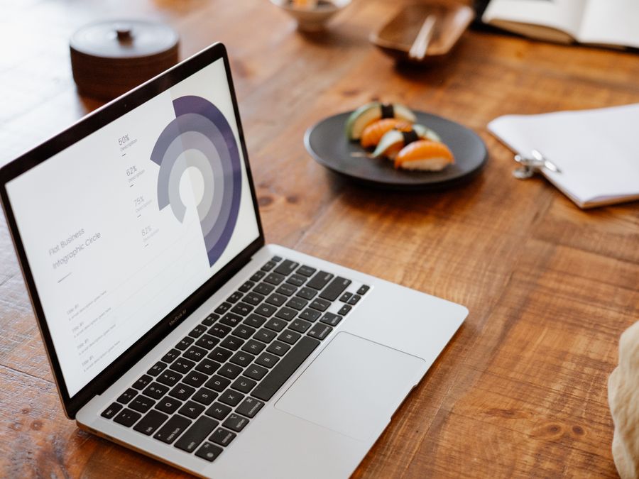 Laptop displaying data on a wooden table with sushi plate, ideal for lifestyle or business themes