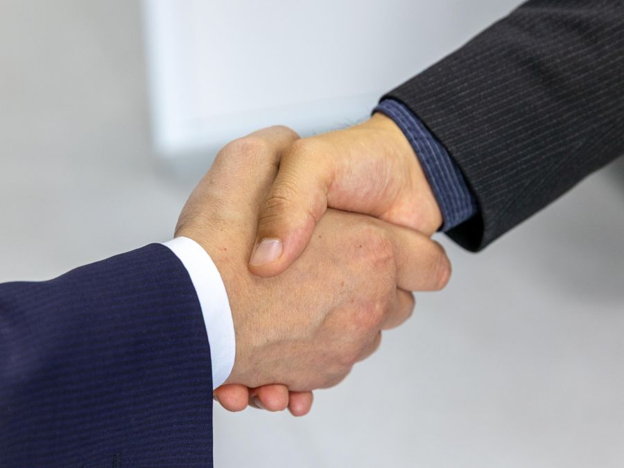 Close-up of two businessmen shaking hands, symbolizing agreement and partnership.
