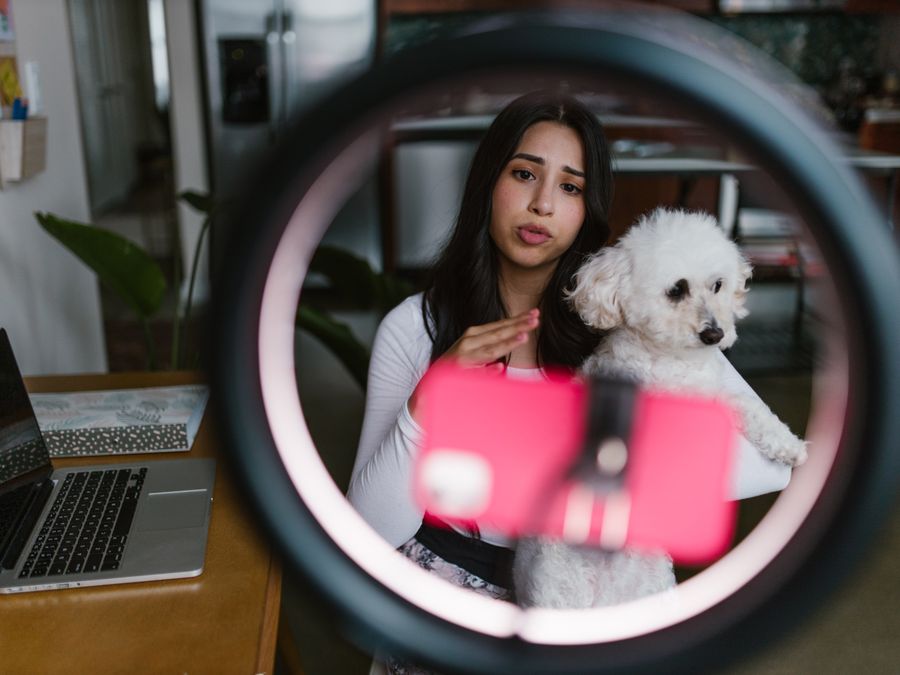 Young woman vlogging with her dog at home, creating content indoors.