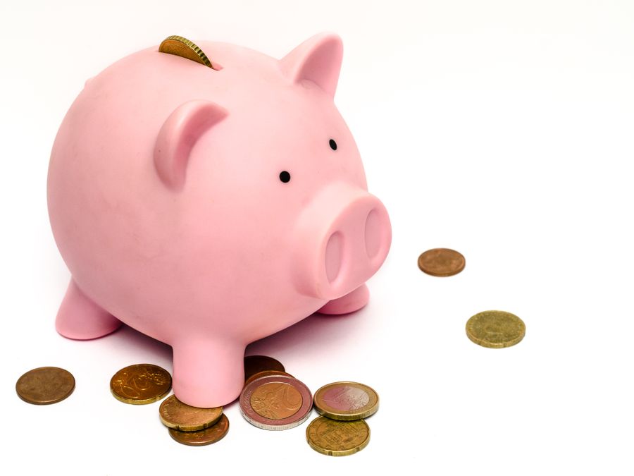 A pink piggy bank surrounded by scattered coins, symbolizing savings and financial investment.