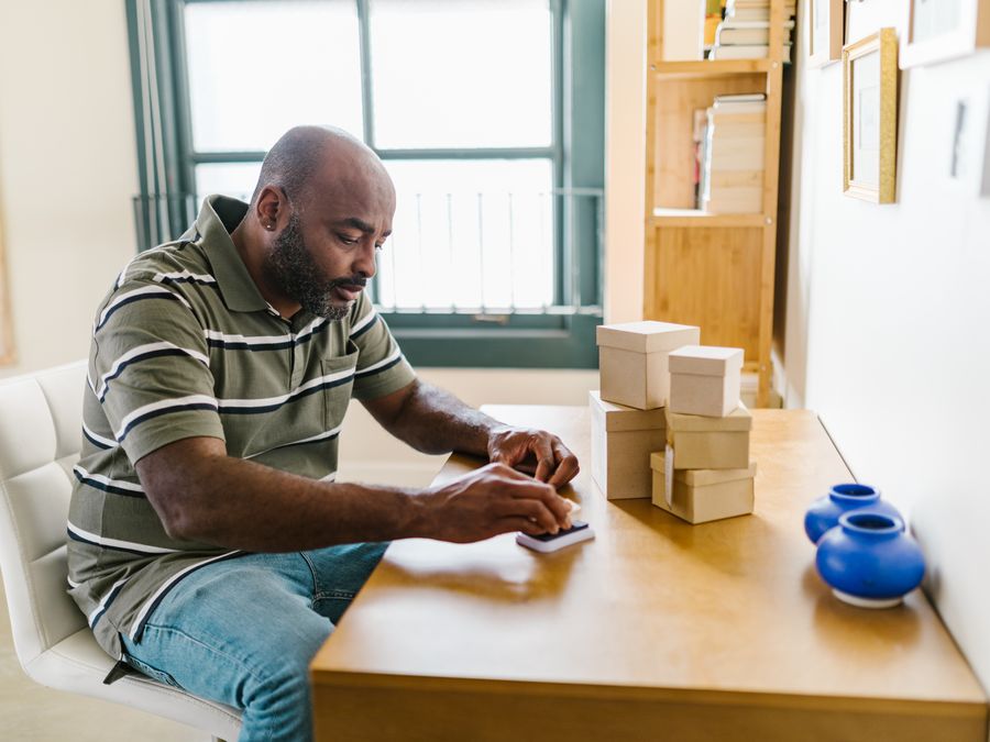Bearded man in home office preparing packages for a small business startup.
