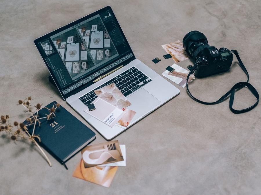 Top view of a creative workspace featuring a laptop, camera, and design materials, ideal for digital artists.