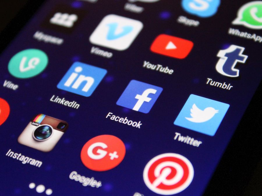 Close-up of a smartphone screen showing various social media app icons such as Facebook and Twitter.