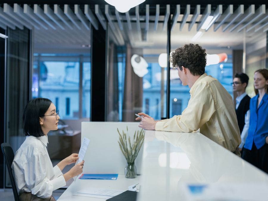 Employees interacting at a sleek office reception desk, fostering professional collaboration.