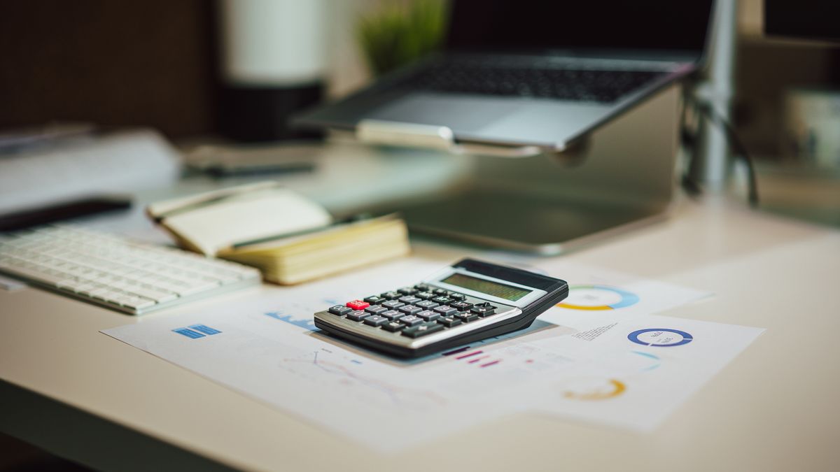 A modern workspace with a laptop, calculator, and documents on a desk, perfect for finance tasks.