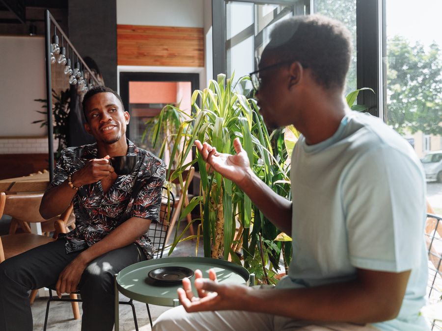 Two friends having a lively conversation over coffee in a cozy coffee shop setting.