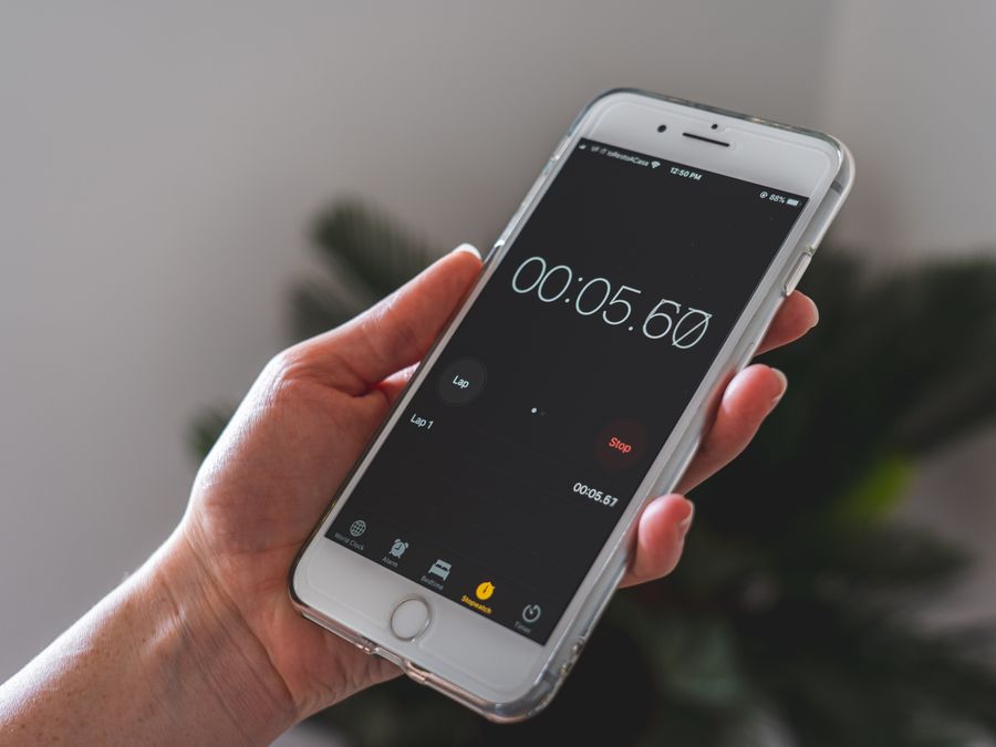 Close-up of a hand holding a smartphone with a stopwatch app running.