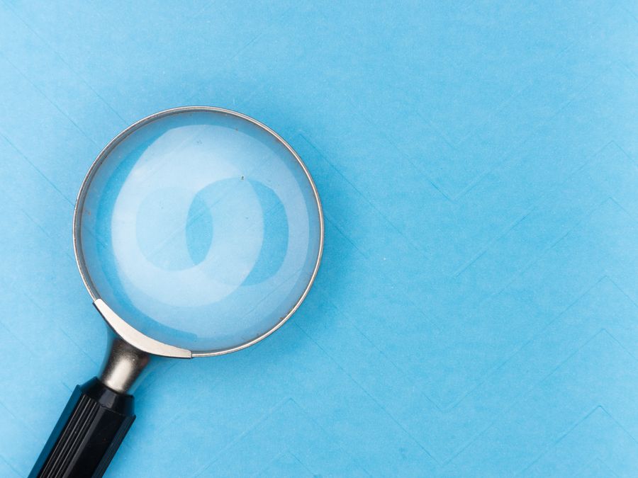 Close-up of a magnifying glass on a blue surface, ideal for search and exploration themes.