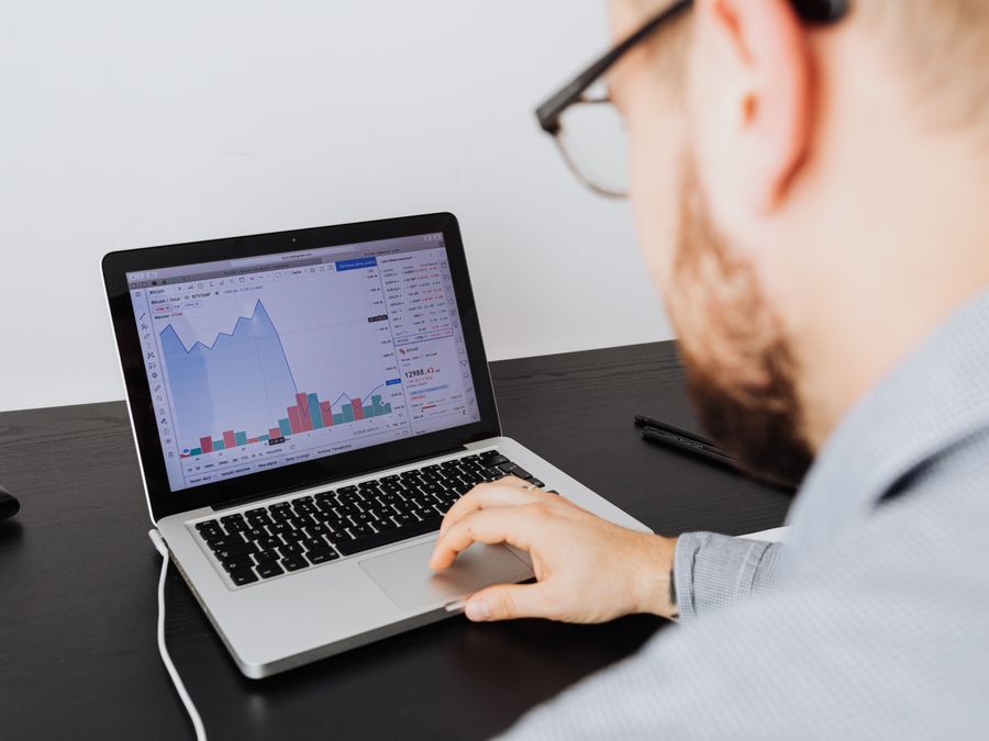 Man working on a laptop analyzing business data and financial graphs indoors.