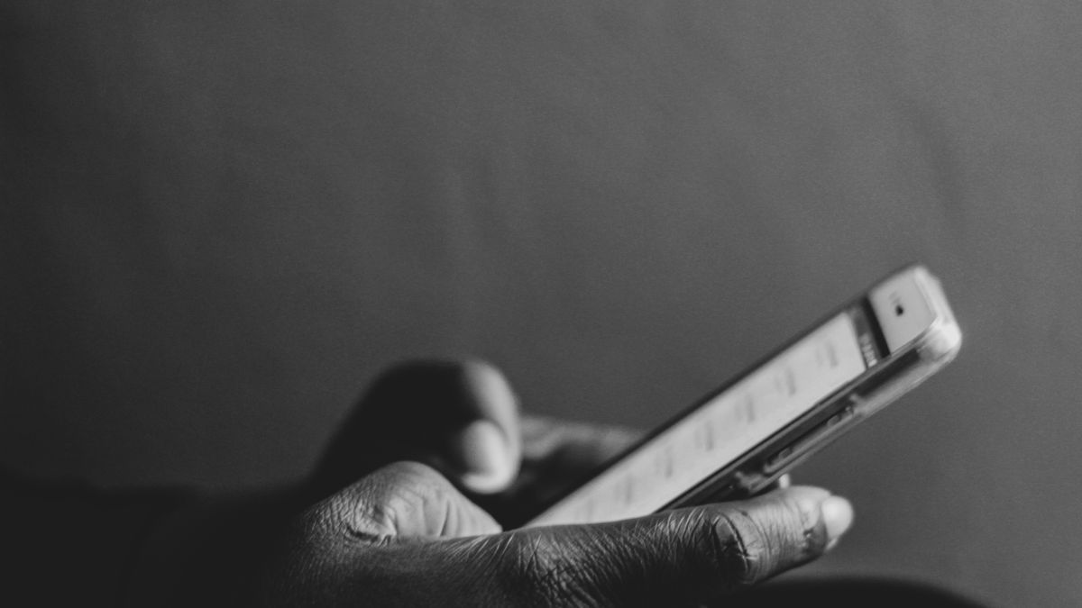 A monochrome image showing a person using a smartphone, emphasizing modern technology.