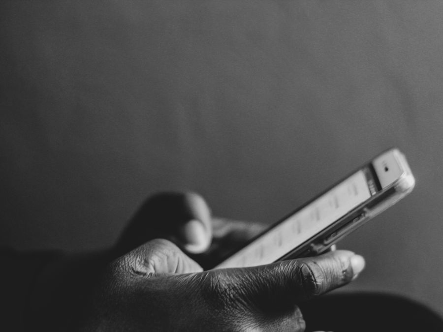 A monochrome image showing a person using a smartphone, emphasizing modern technology.