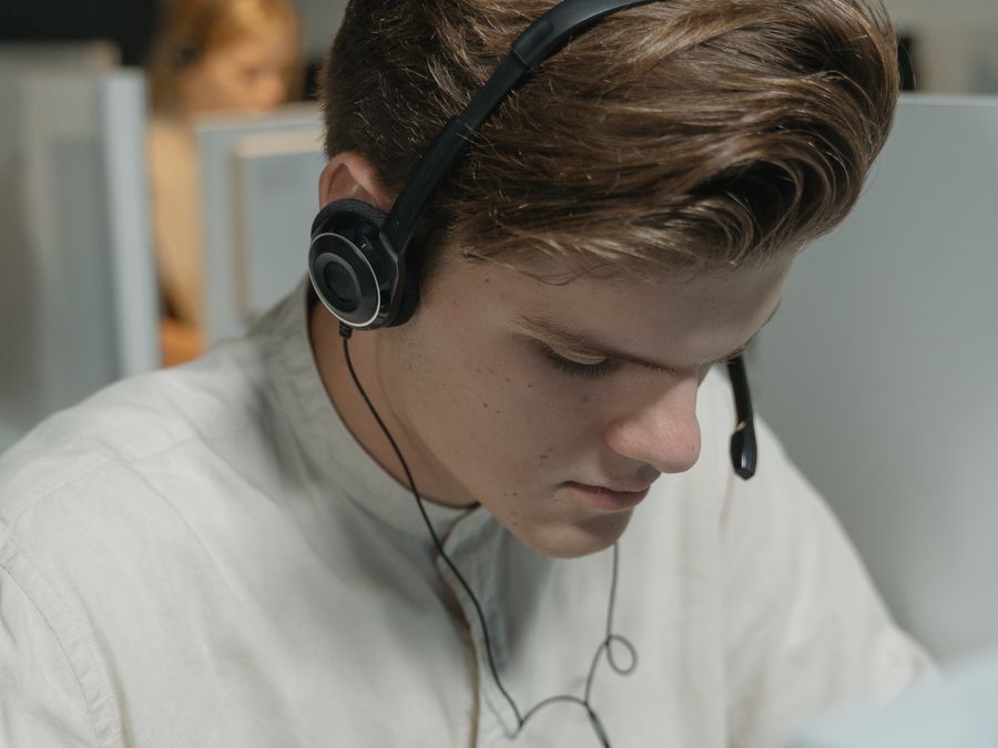 A call center agent wearing headphones focuses on providing customer support in an office setting.