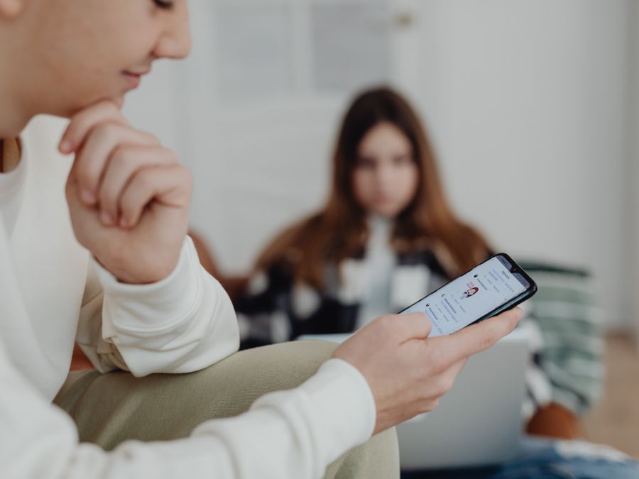 Teens using smartphones indoors with a blurred background, suggesting social media engagement.