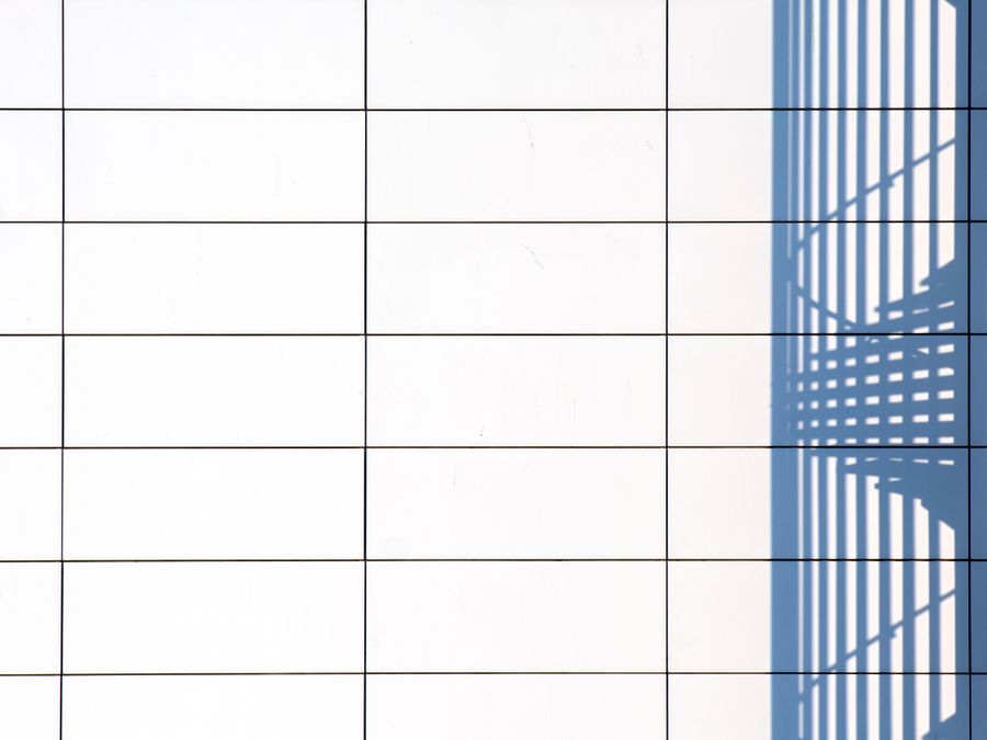 Minimalist image of shadow casting on a white tiled wall, perfect for modern design use.