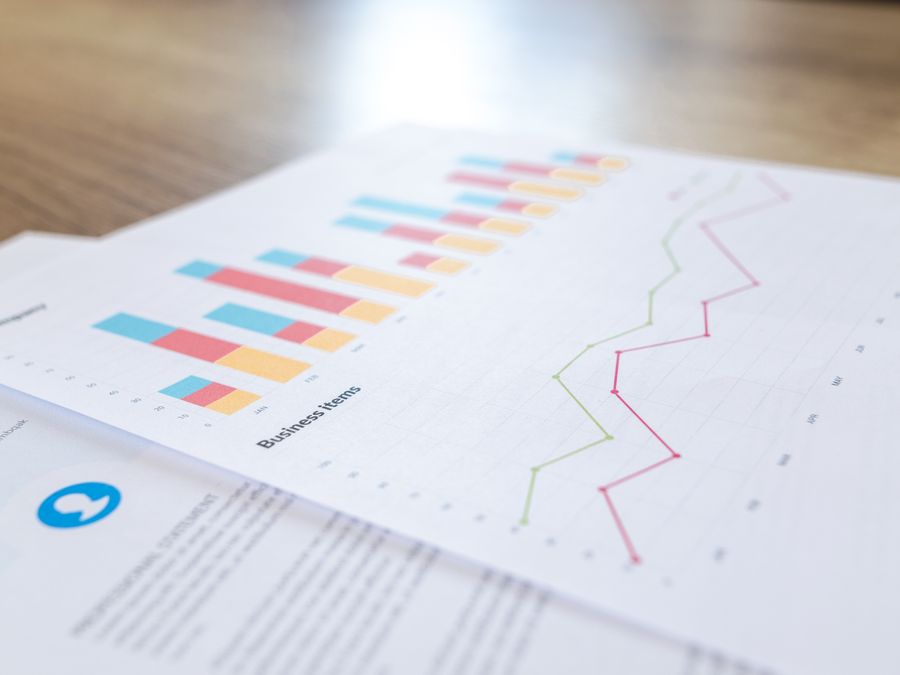 A close-up view of a business document with charts and graphs on a wooden desk.