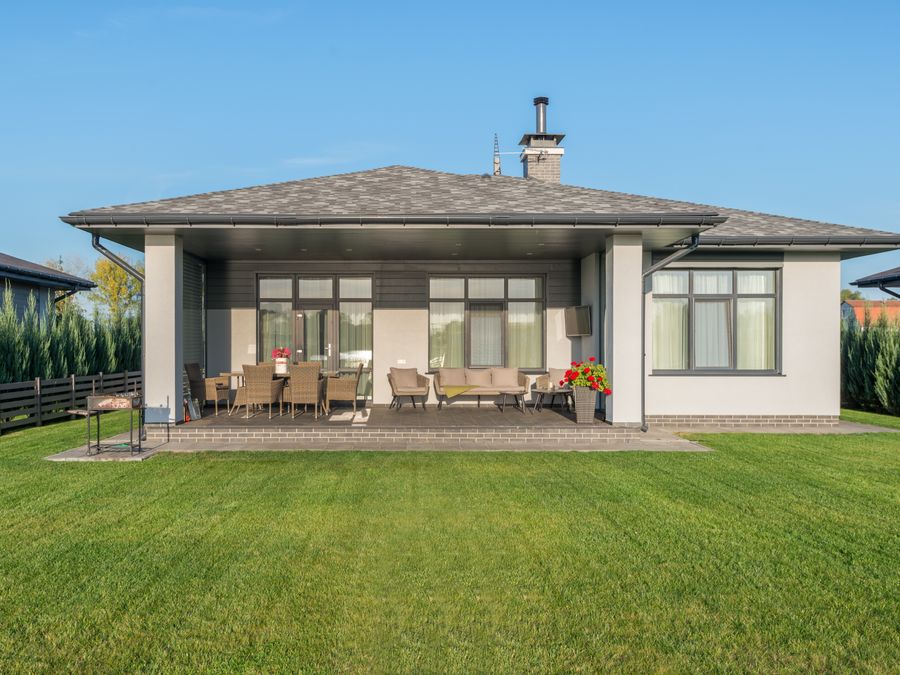 Contemporary house exterior with a large backyard patio and manicured lawn.