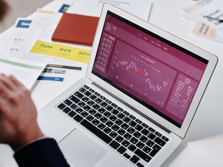 Businessperson reviewing data analytics on a laptop screen in an office setting.
