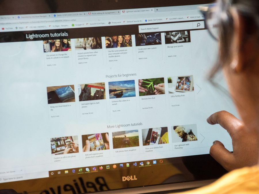 A woman exploring Adobe Lightroom tutorials online for learning and photo editing.