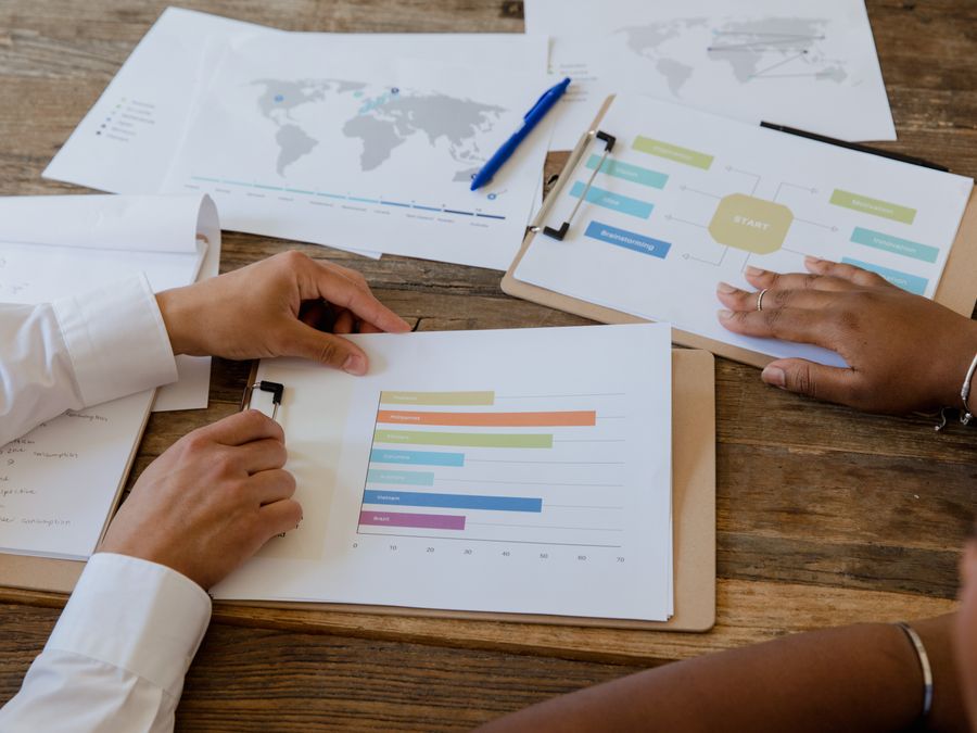 Top view of colleagues discussing charts and graphs on a wooden table during a business meeting.