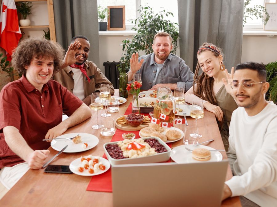 A group of friends sharing a joyful meal and engaging in a video call. Diverse, happy scene.
