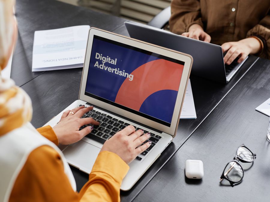 Two professionals work on laptops focusing on digital advertising in an office setting.