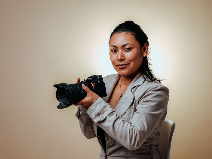 Portrait of a professional photographer holding a camera in a studio setting.