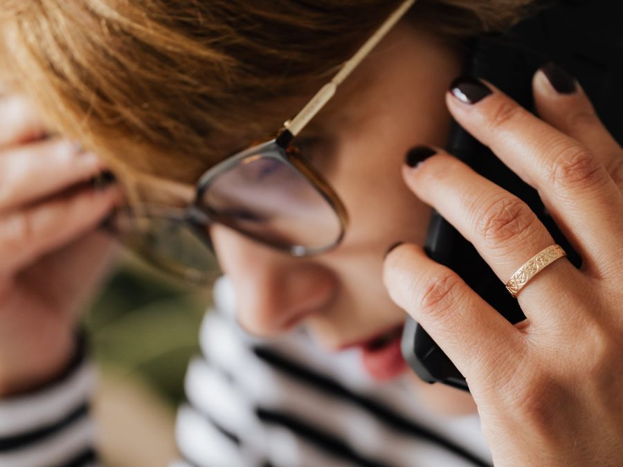 Side view of thoughtful anxious woman in eyeglasses touching head while having phone conversation