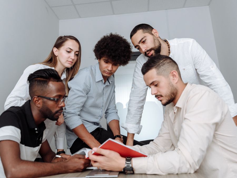 A multicultural team engaged in a collaborative office meeting, discussing ideas around a table.