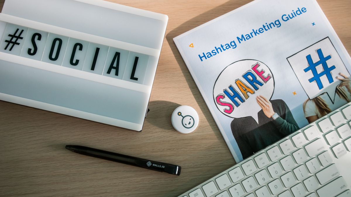 A desktop setup with social media marketing essentials including a keyboard, lightbox, and guide.