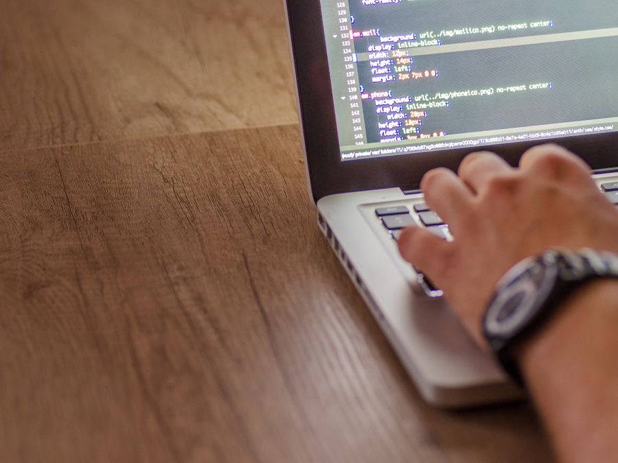 Close-up of a person coding on a laptop, showcasing web development and programming concepts.