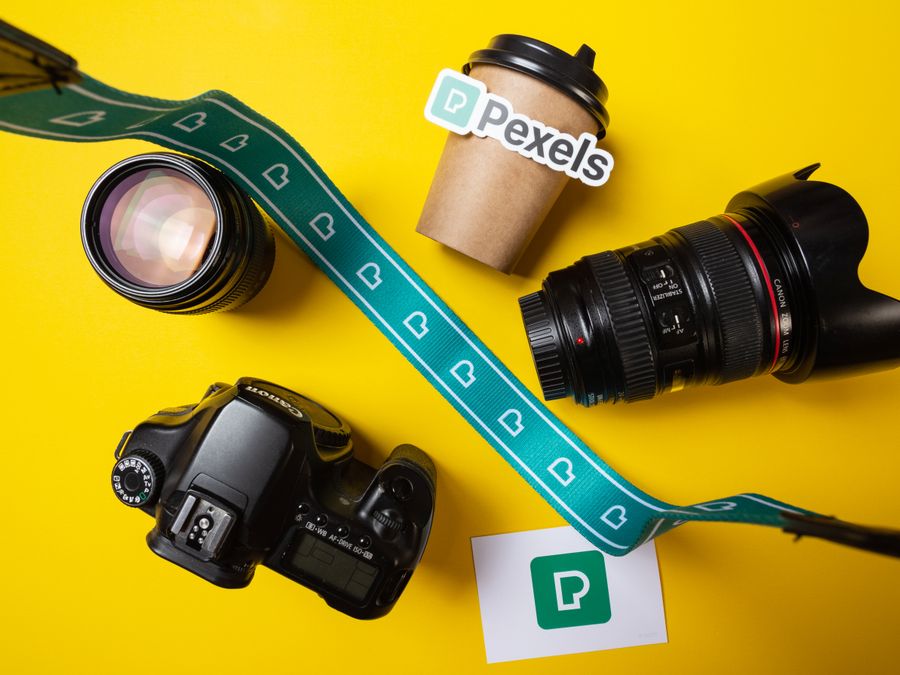 Flat lay of camera, lens, and coffee cup on a vibrant yellow background.